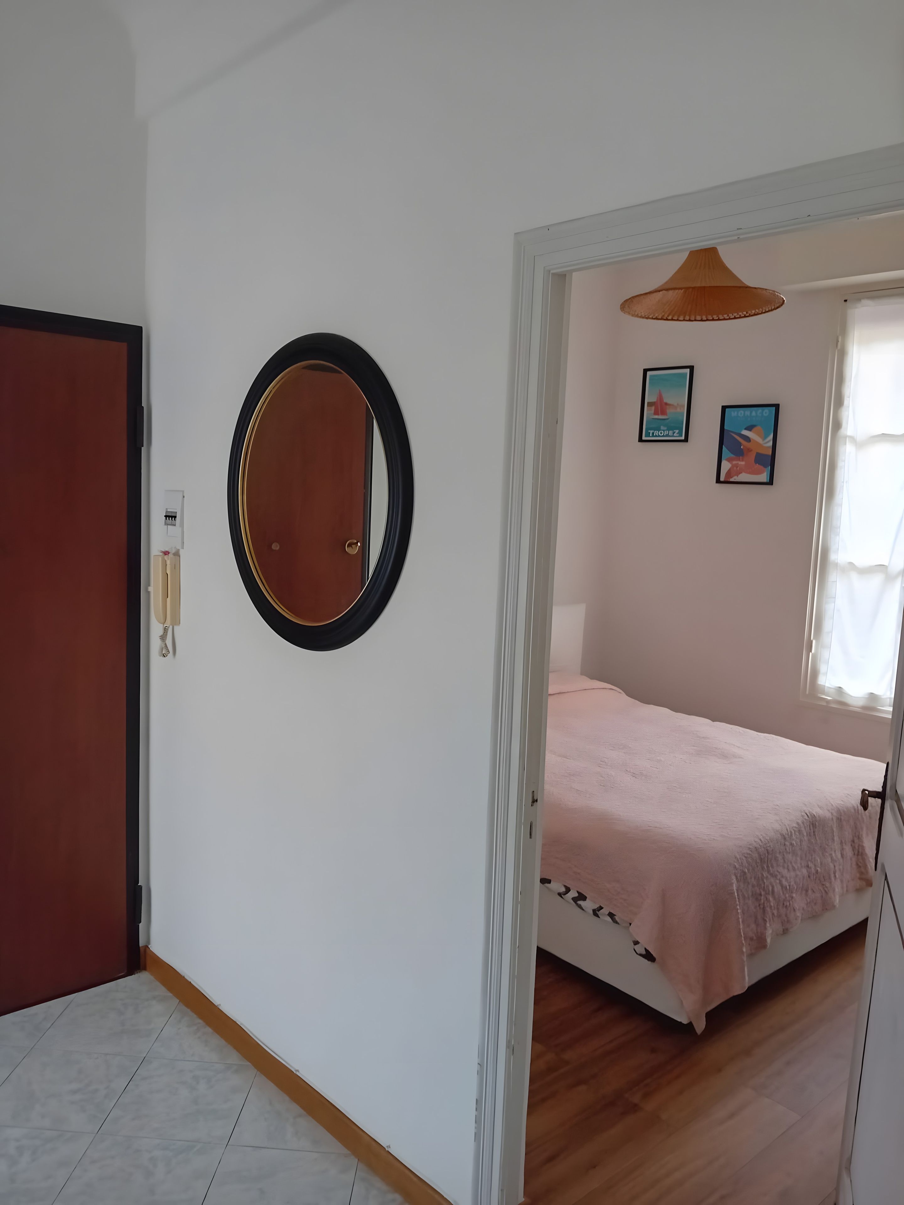 A bedroom with a bed, a door, a mirror, and two wall-mounted pictures.