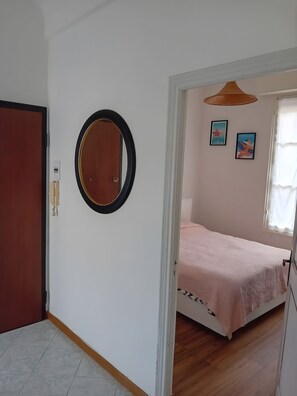 A bedroom with a bed, a door, a mirror, and two wall-mounted pictures. - Il Gattino di Sanremo 1 – Relaxing Apartment with Wi-Fi, AC & Parking (Sanremo)