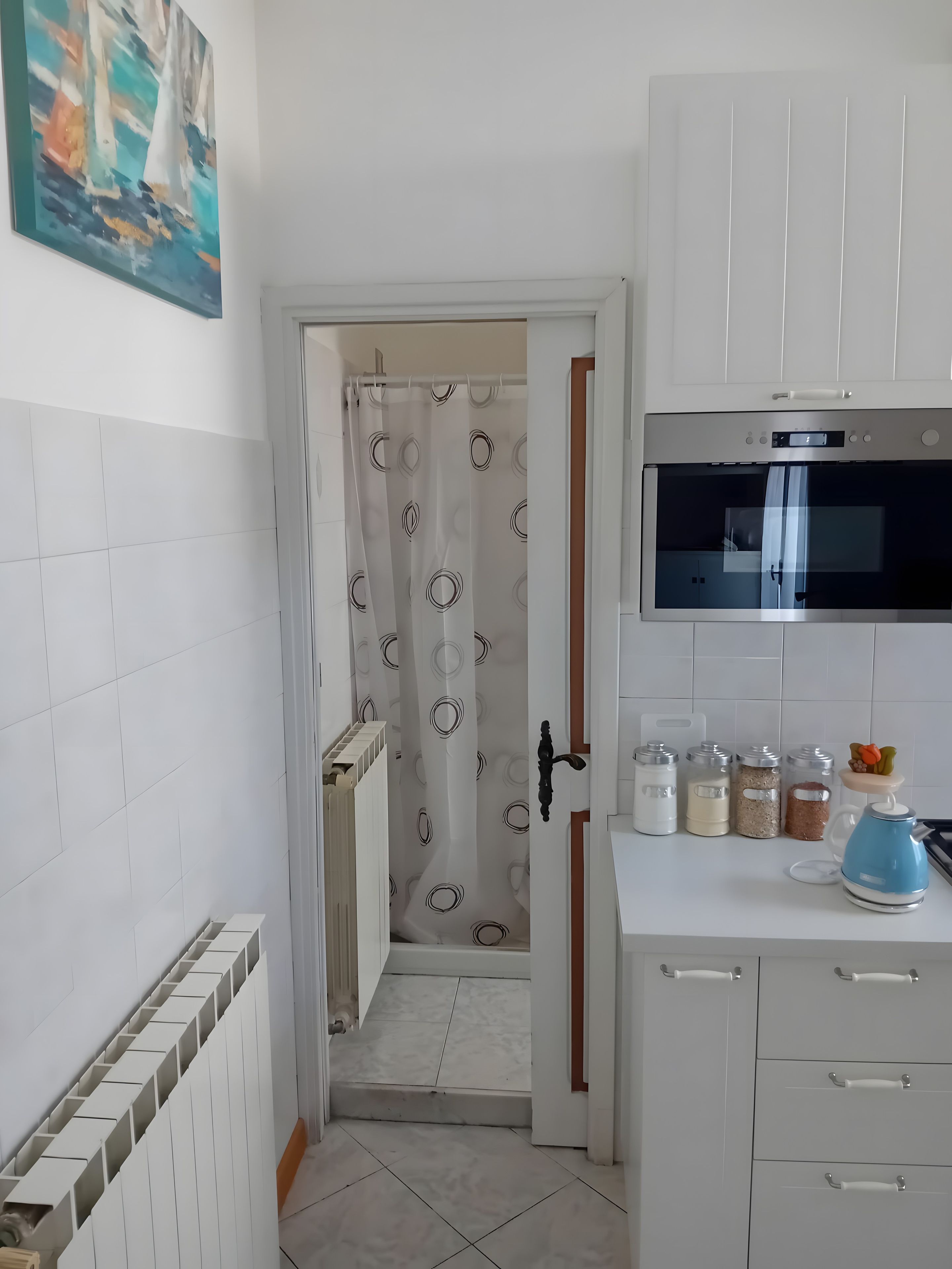A kitchen with white cabinets, a microwave, and a kettle.