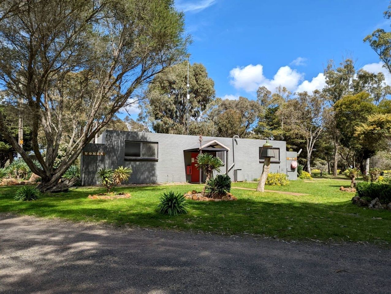 A single-story building with a red door, surrounded by a well-maintained lawn and trees.