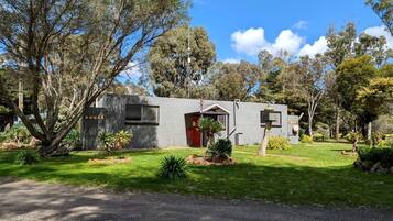 A single-story building with a red door, surrounded by a well-maintained lawn and trees.