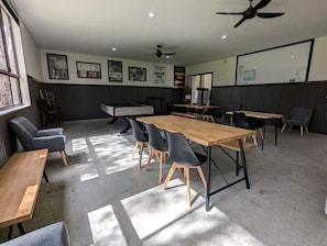 Uma sala de conferências com uma mesa comprida, cadeiras e um ventilador de teto.