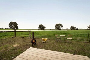 An outdoor area with a wood-burning stove, a wooden deck, and a seating arrangement.