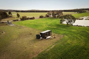 Une propriété rurale comprenant un grand champ, un petit bâtiment et un étang.