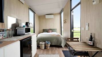 Una habitación compacta con cama, kitchenette y comedor.