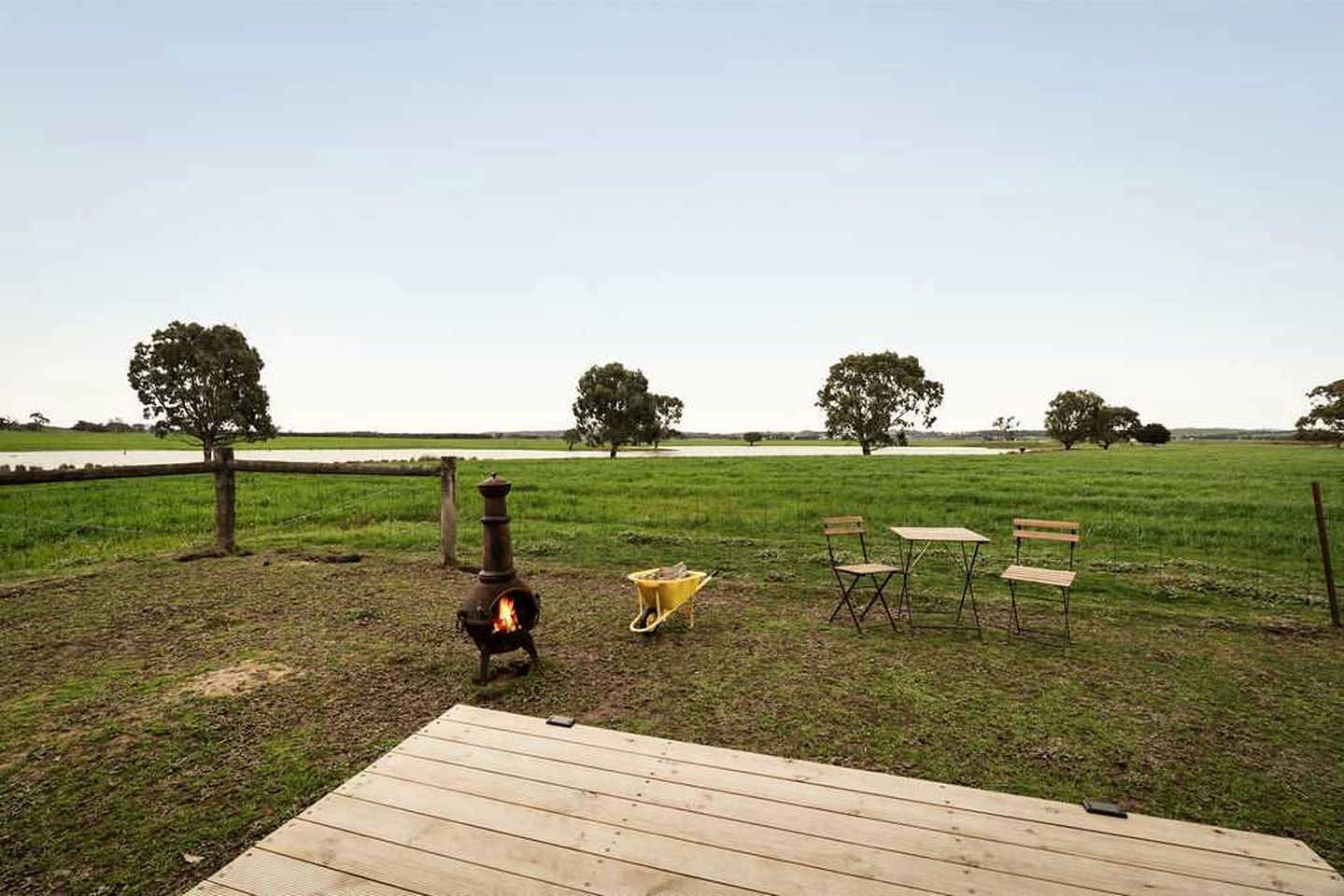 An outdoor area with a wood-burning stove, a wooden deck, and a seating arrangement.