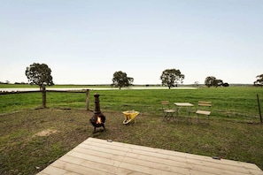 An outdoor area with a wood-burning stove, a wooden deck, and a seating arrangement.