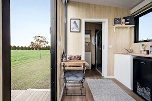 A compact kitchen with a dining area, a view of a grassy field, and a door leading to a bathroom.