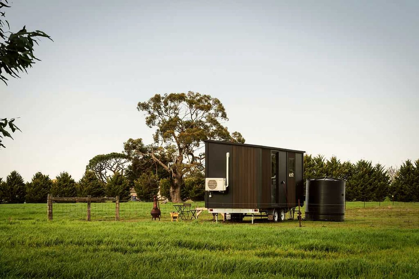 Een stacaravan met een kitchenette en een waterreservoir in een grasveld.