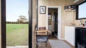 A compact kitchen with a dining area, a view of a grassy field, and a door leading to a bathroom.