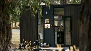 A small cabin with a door and windows, surrounded by trees.