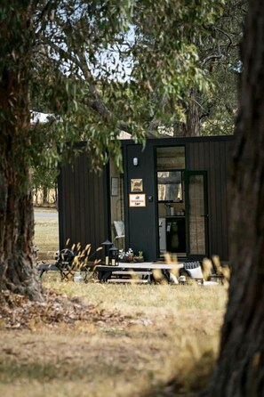 A small cabin with a door and windows, surrounded by trees. - Delightfully Tiny House Ideal for a Peaceful Escape in Springmount, Victoria (Creswick)