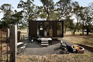 Uma cabana moderna com um espaço de varanda, lareira e mesa de jantar.