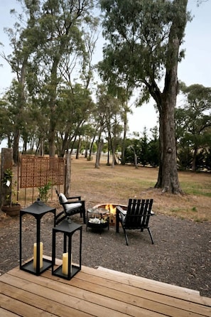 An outdoor seating area with a fire pit, two chairs, and a table.