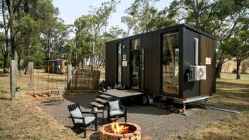 A modern, compact mobile home with a fire pit and outdoor seating area.