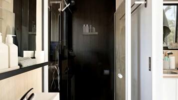 A modern bathroom with a glass-enclosed shower, a white sink, and a wooden vanity.