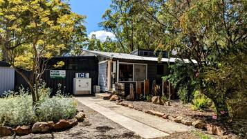 A rustic building with a concrete pathway leading to the entrance, surrounded by natural vegetation and trees.