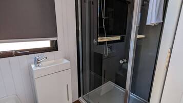 A bathroom with a glass shower enclosure, a white sink, and a mirror above the sink.