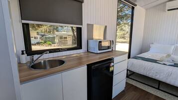 A compact kitchenette with a sink, microwave, and a compact refrigerator.