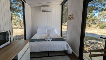 A bedroom with a bed, a microwave, and a view of the outdoors.