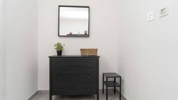 A dark wooden dresser with drawers, a small potted plant, and a wicker basket on top.