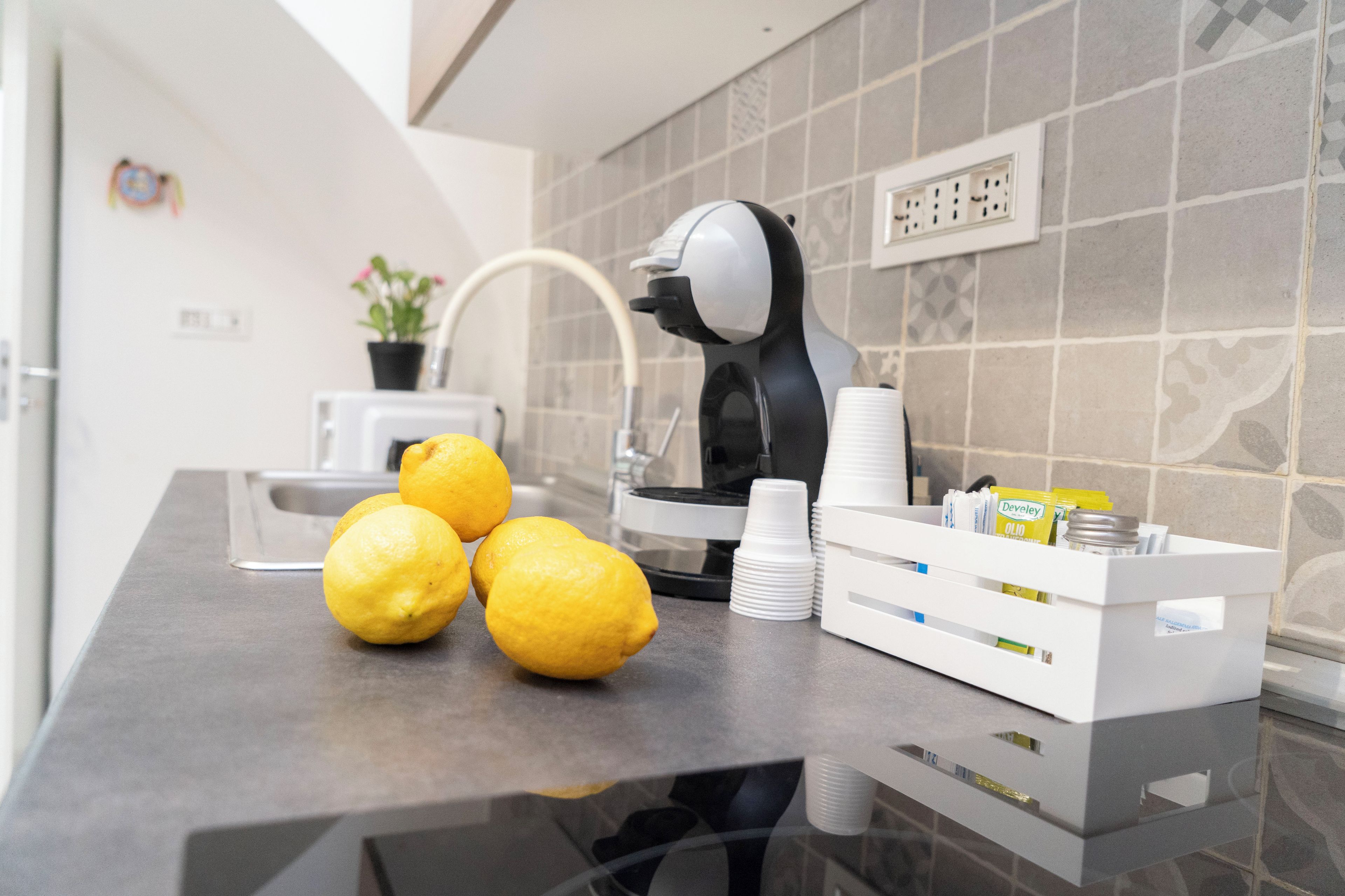 Un ripiano in cucina con limoni, una macchina da caffè e un erogatore bianco.
