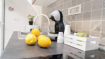 Un ripiano in cucina con limoni, una macchina da caffè e un erogatore bianco.
