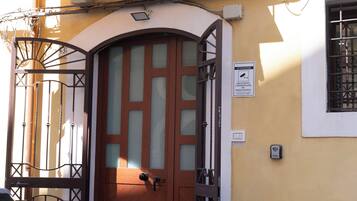 A wooden door with a glass panel, a metal gate, and a security camera on the wall.