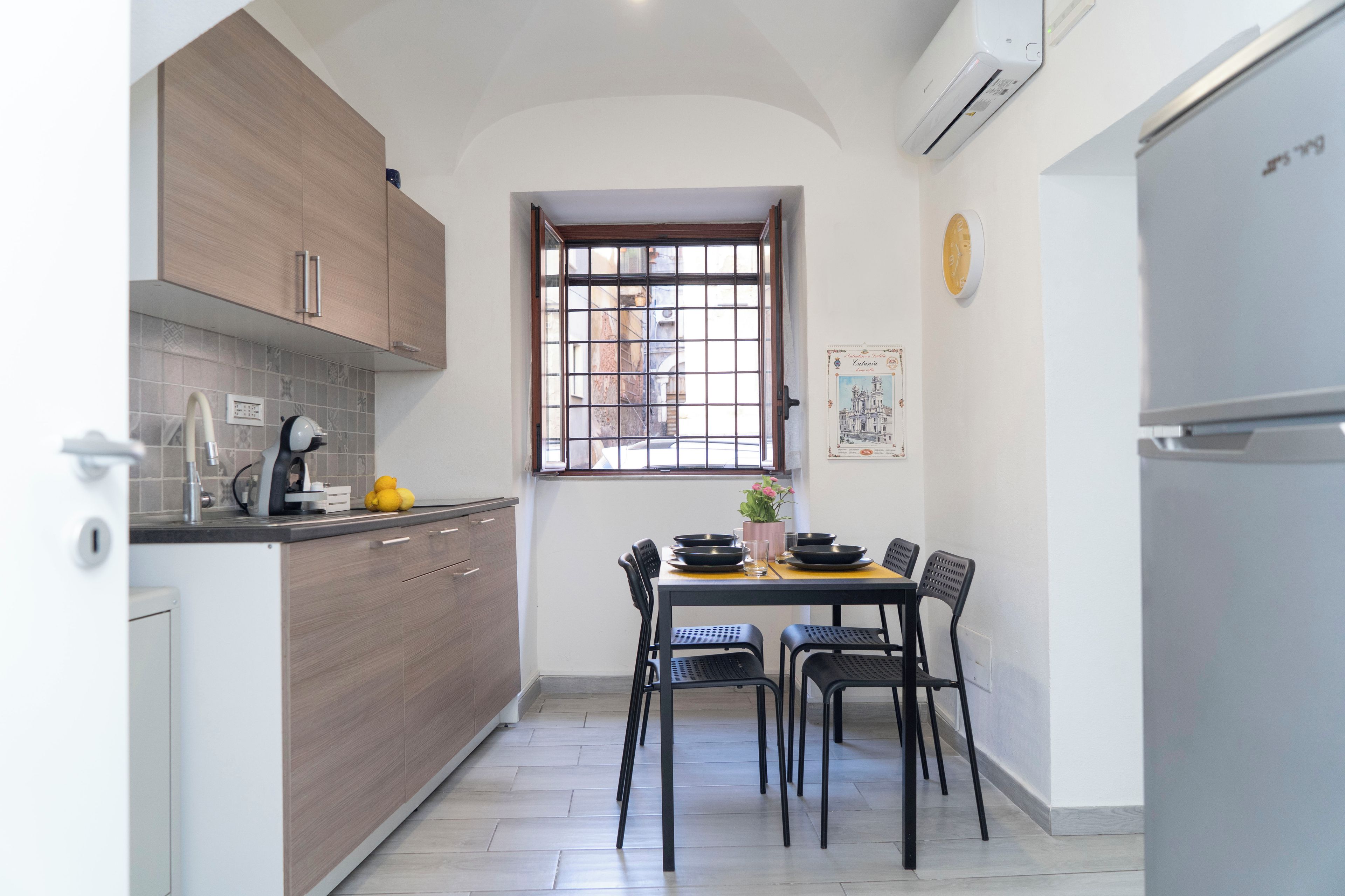 Una cucina compatta con zona pranzo, caratterizzata da una finestra vista, una sveglia e un frigorifero.