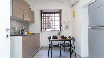 Una cucina compatta con zona pranzo, caratterizzata da una finestra vista, una sveglia e un frigorifero.