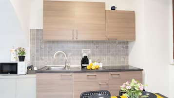 Una cucina compatta con mobili in legno, un forno a microonde, un lavandino e un'area pranzo con tavolo e sedie.