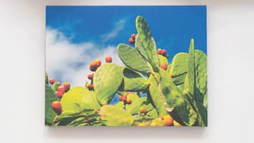 A cactus with green leaves and red fruits against a blue sky.