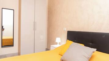 A hotel room with a bed, a wardrobe, a nightstand, and a wall-mounted lamp.
