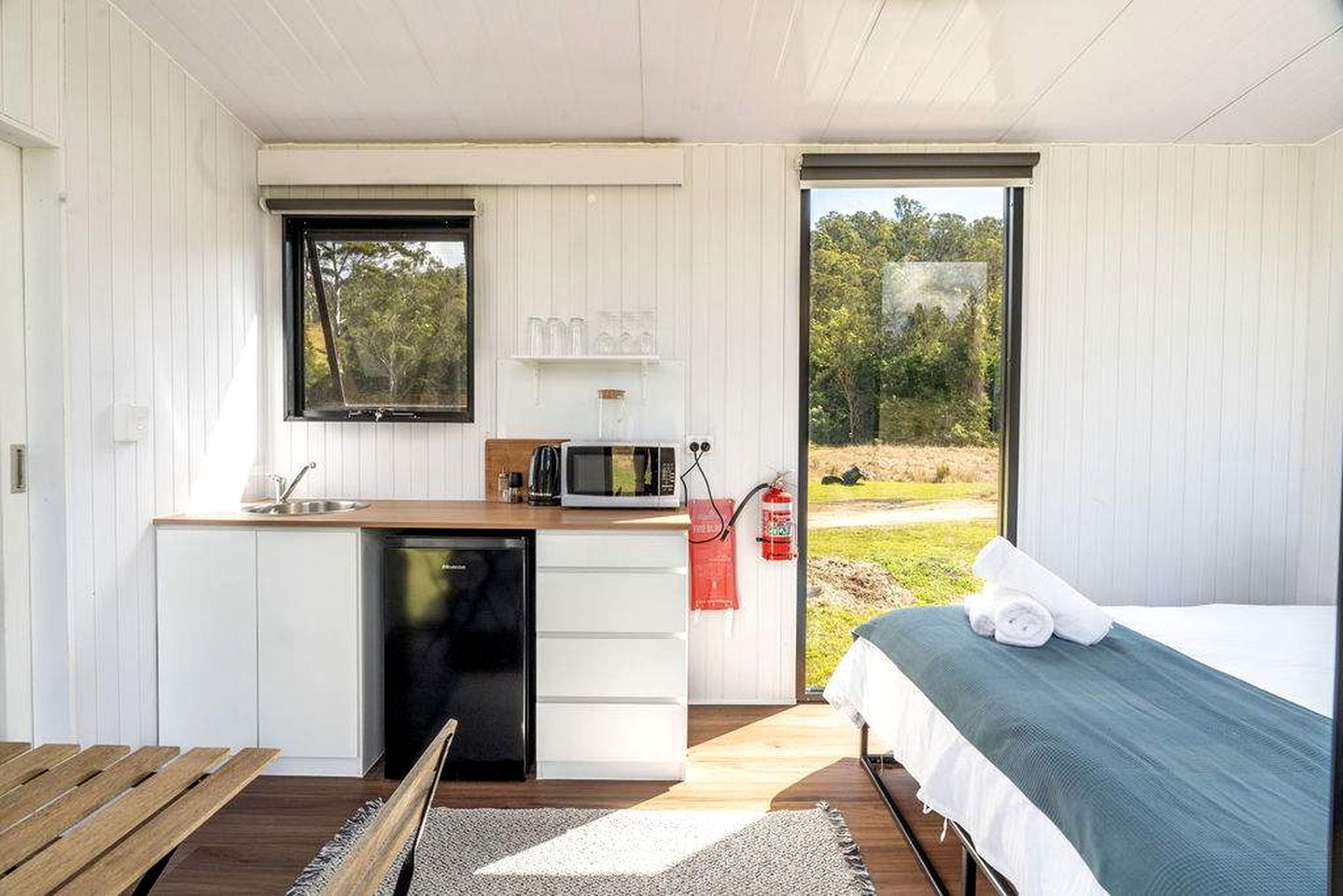 A compact room with a bed, a small kitchenette, and a view of the outdoors.