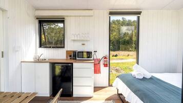 Una habitación compacta con cama, kitchenette pequeño y vista al exterior.
