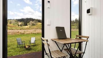 Une pièce avec vue sur un champ verdoyant, une table avec des chaises et un ordinateur portable posé sur la table.