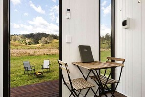 Une pièce avec vue sur un champ verdoyant, une table avec des chaises et un ordinateur portable posé sur la table.