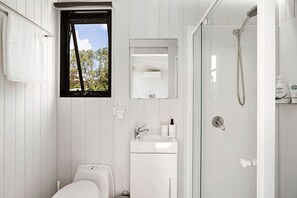 Une salle de bain moderne équipée de toilettes, d’un lavabo et d’une douche.