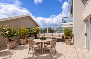 A rooftop terrace with a round table and chairs, a sofa, and potted plants. - Gorgeous 3-bedroom apartment in Muizenberg. (Cape Town)