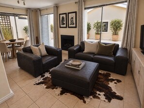 Ein Wohnzimmer mit zwei Sofas, einem Couchtisch und einem Kamin. Üchtis und ein Fernseher stehen auf einer Holzkommode.