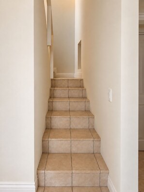 A staircase with beige tiles leading to a landing. - Gorgeous 3-bedroom apartment in Muizenberg. (Cape Town)