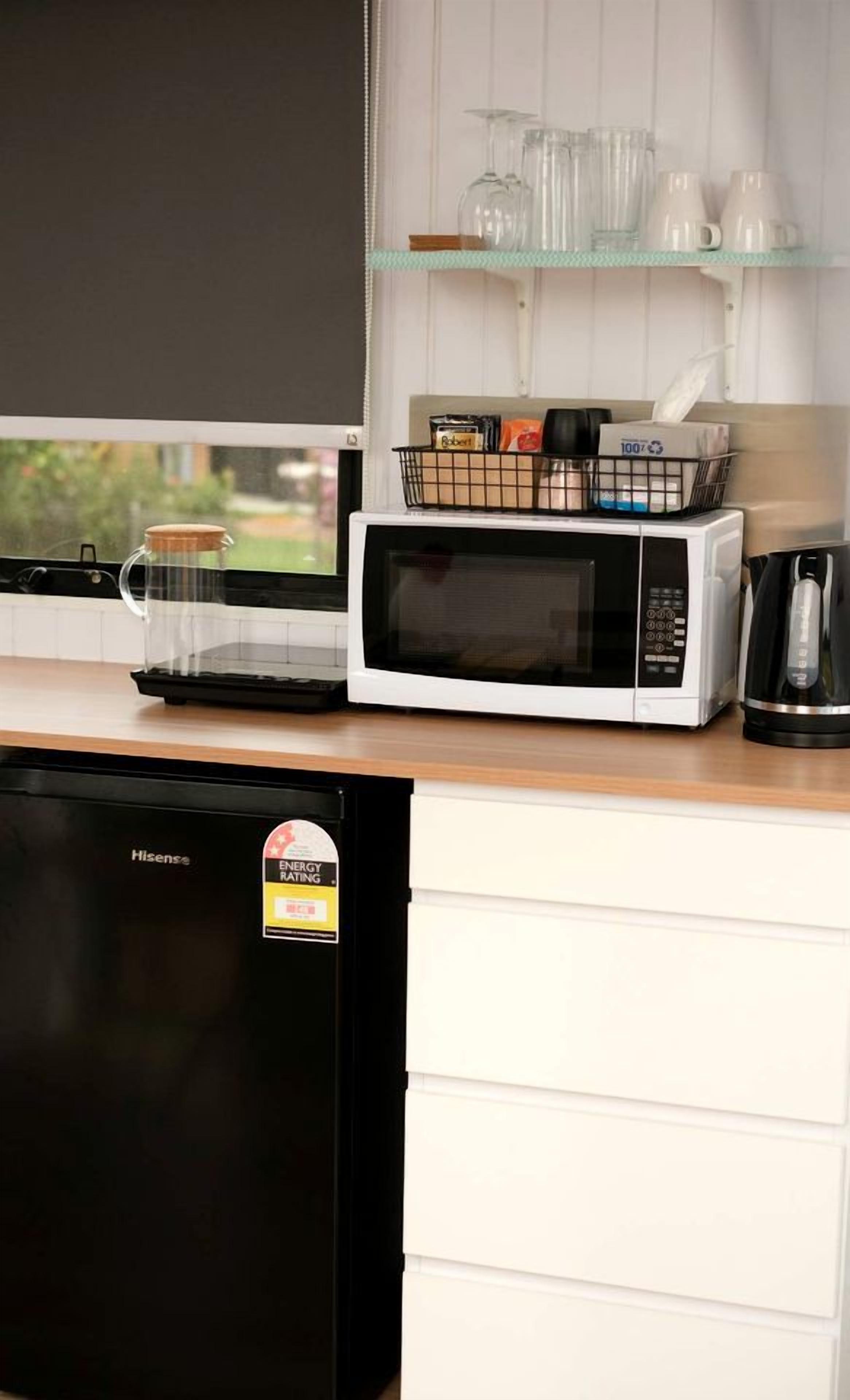 A kitchen with a microwave, a coffee maker, and a refrigerator.
