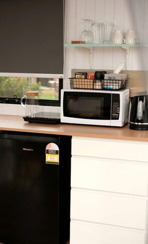 Cozinha equipada com micro-ondas, cafeteira e frigorífico.