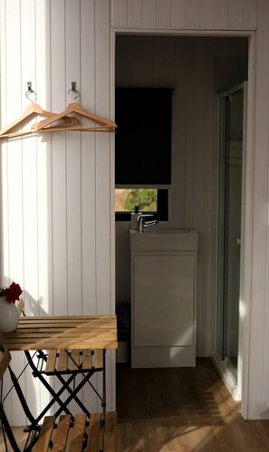 A small bathroom with a sink and window, wooden furniture, and a door leading to another room. - Starry Night Farmstay in Forbes, New South Wales (Forbes)