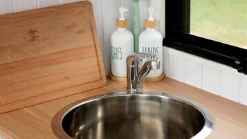 A kitchen with a stainless steel sink, wooden countertop, and a window with a view.