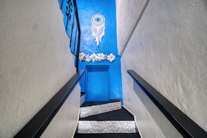 A staircase with a blue door at the bottom, leading to a room with a patterned floor. - Spacious unit in the historical Zonal Colonial with a view of the Caribbean Sea. (CIUDAD COLONIAL)