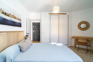 A bedroom with a bed, a desk, a chair, a door, and a wall-mounted mirror. - Apartment in Nerja Near Torrecilla Beach (Nerja)