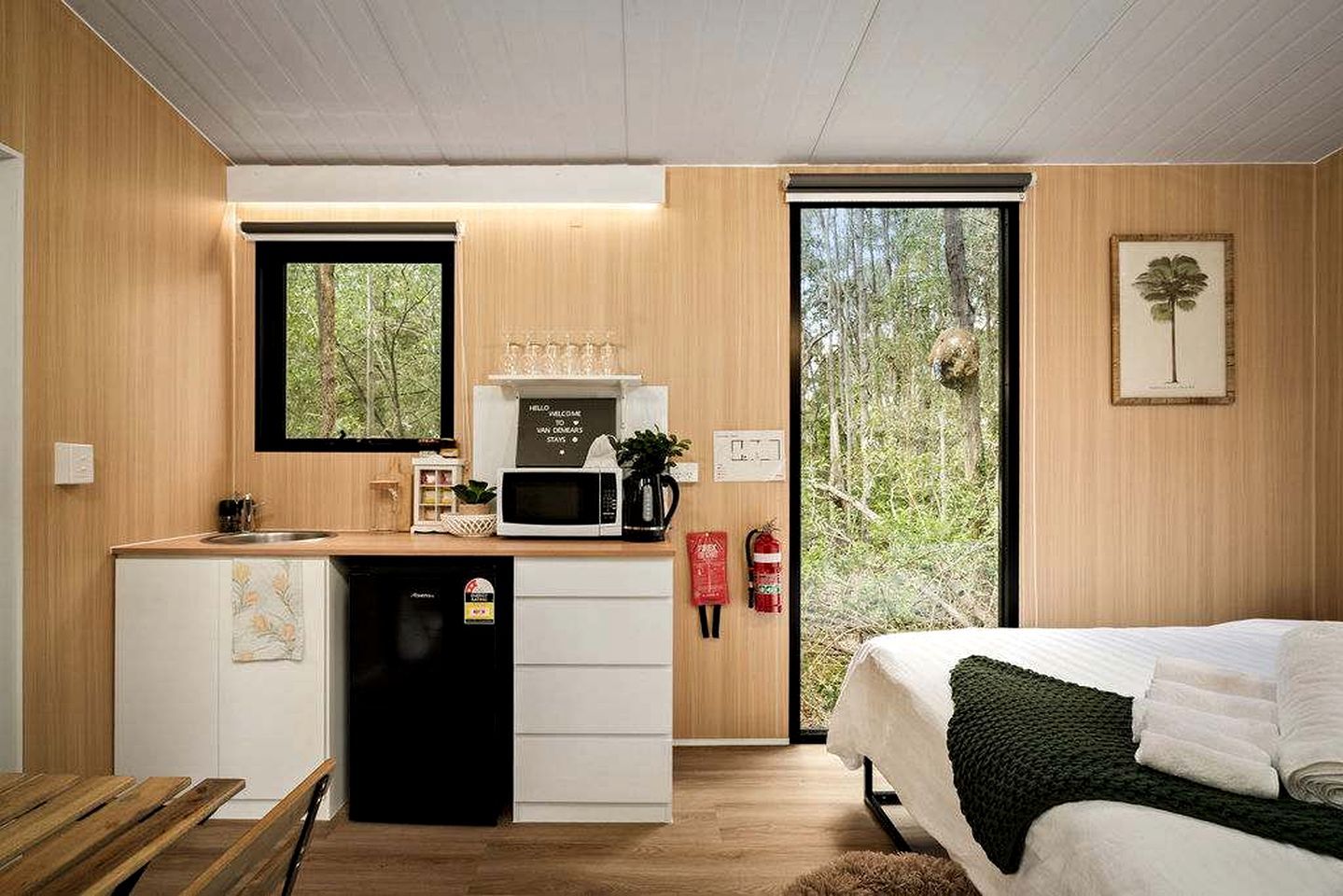 Ein kleines Zimmer mit einer Küchenzeile, einem Bett und einem großen Fenster.
