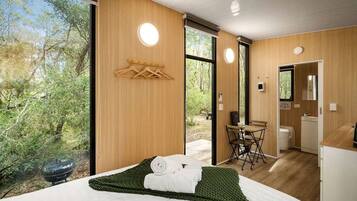 Une chambre d’hôtel moderne dotée d’un grand lit, offrant une vue sur l’extérieur, comprenant un petit coin repas et une salle de bain.