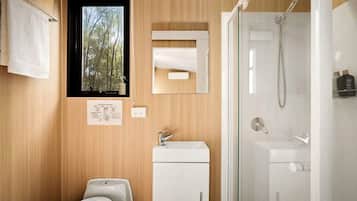 A modern bathroom with a wooden wall, a window, a mirror, a sink, and a shower.